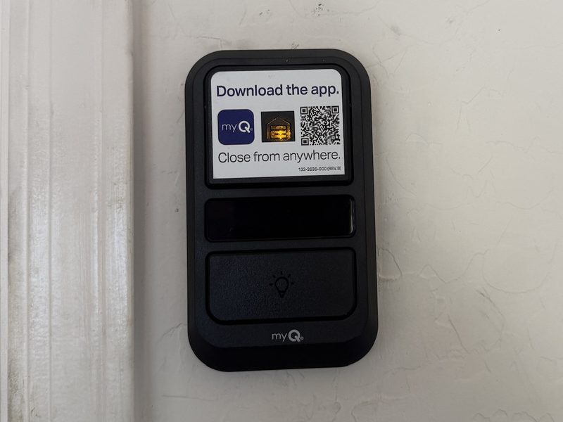 A myQ wall control panel for a garage door opener mounted beside the door