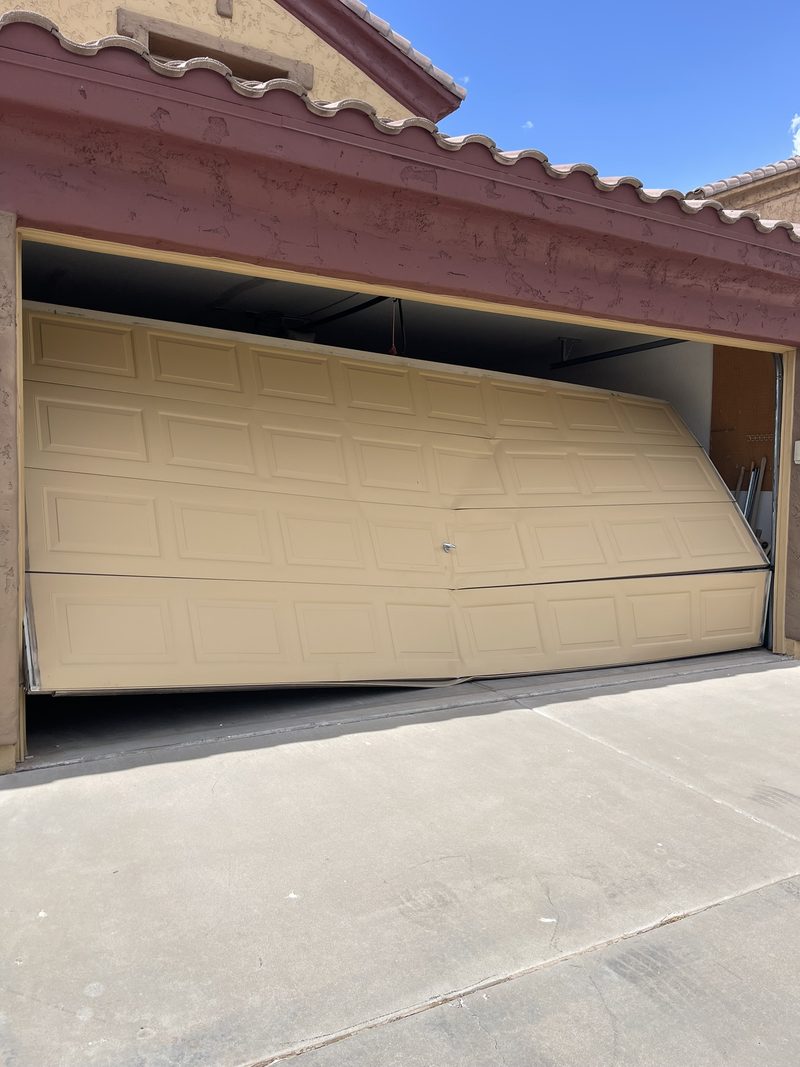 Garage door hanging off its tracks and buckled across the opening
